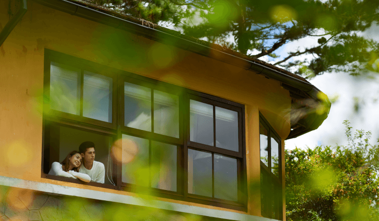 Casal olhando pela janela da casa sustentável